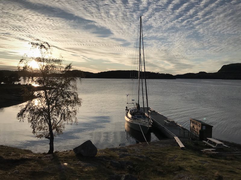 Die Segelyacht Aroha ist in einer Abendstimmung mit weichen Wolkenmustern an einem Steg zu sehen.